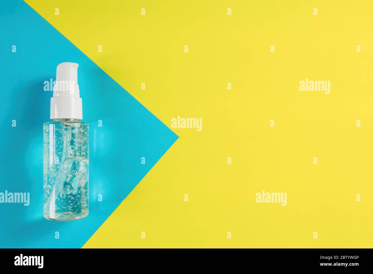 Alcohol gel on blue and yellow background. Top view of antibacterial soap sanitizer. Hygiene concept for prevent the spread corona virus. Copy space Stock Photo