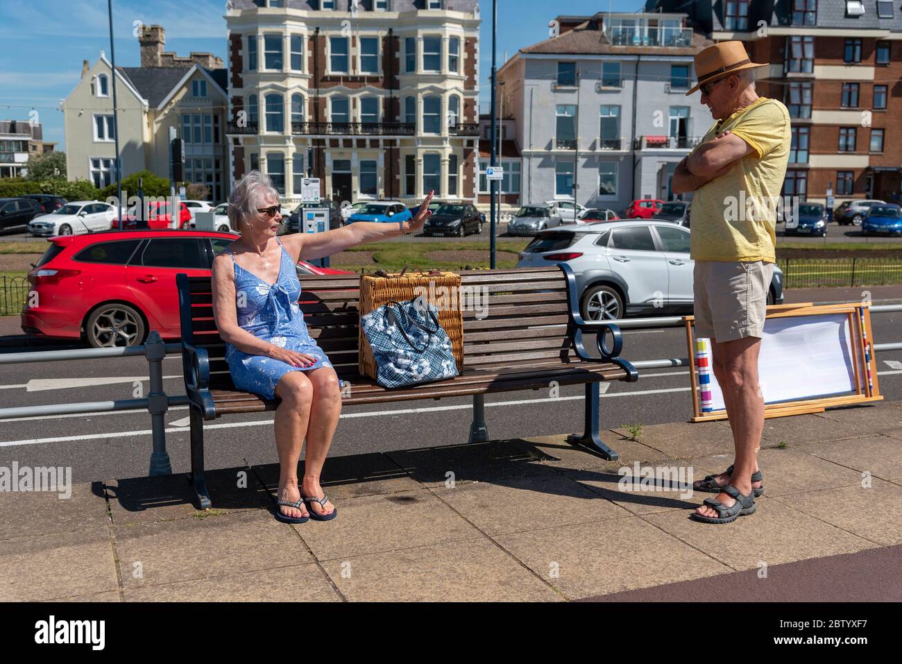 Southsea, Portsmouth, Southern England, UK. 2020. Woman sitting on a bench self distancing during the Corvid-19 outbreak. No space for the man to sit Stock Photo