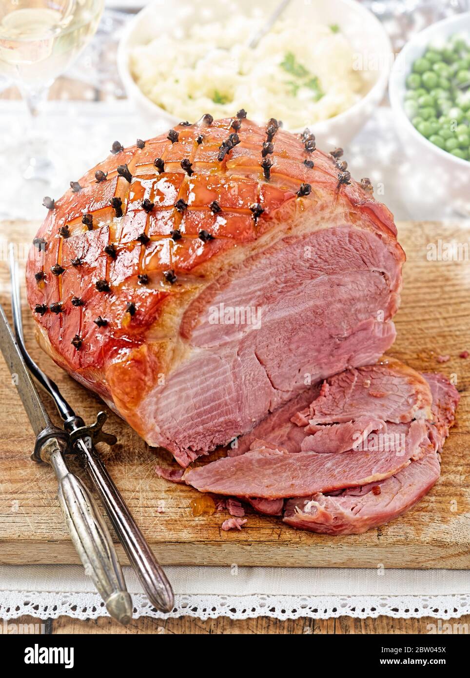 Festive ham glazed with cloves sliced on Christmas table Stock Photo