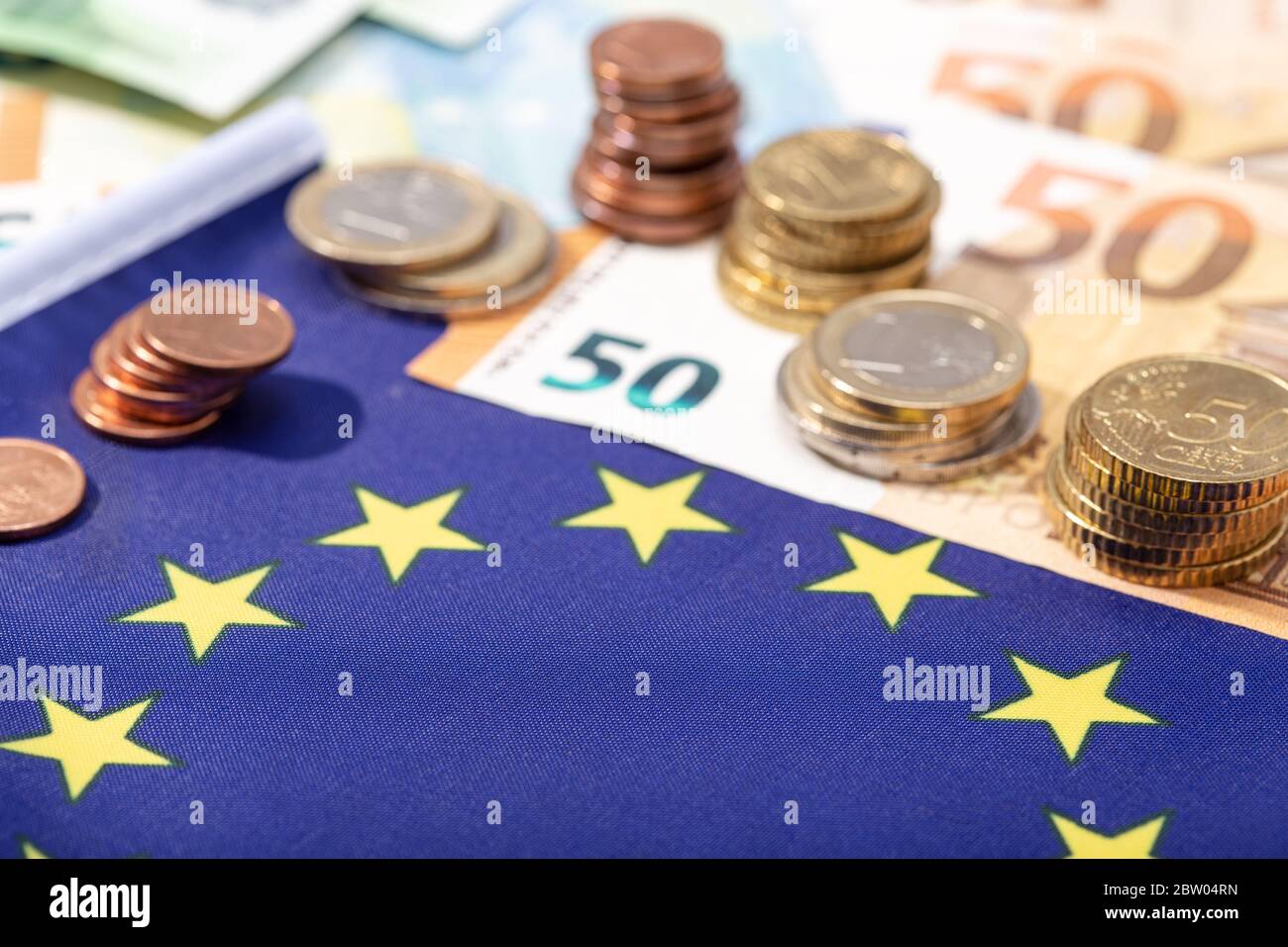 European Union financial stimulus on coronavirus Covid-19 pandemic concept. European Union flag with euro bills and coins Stock Photo