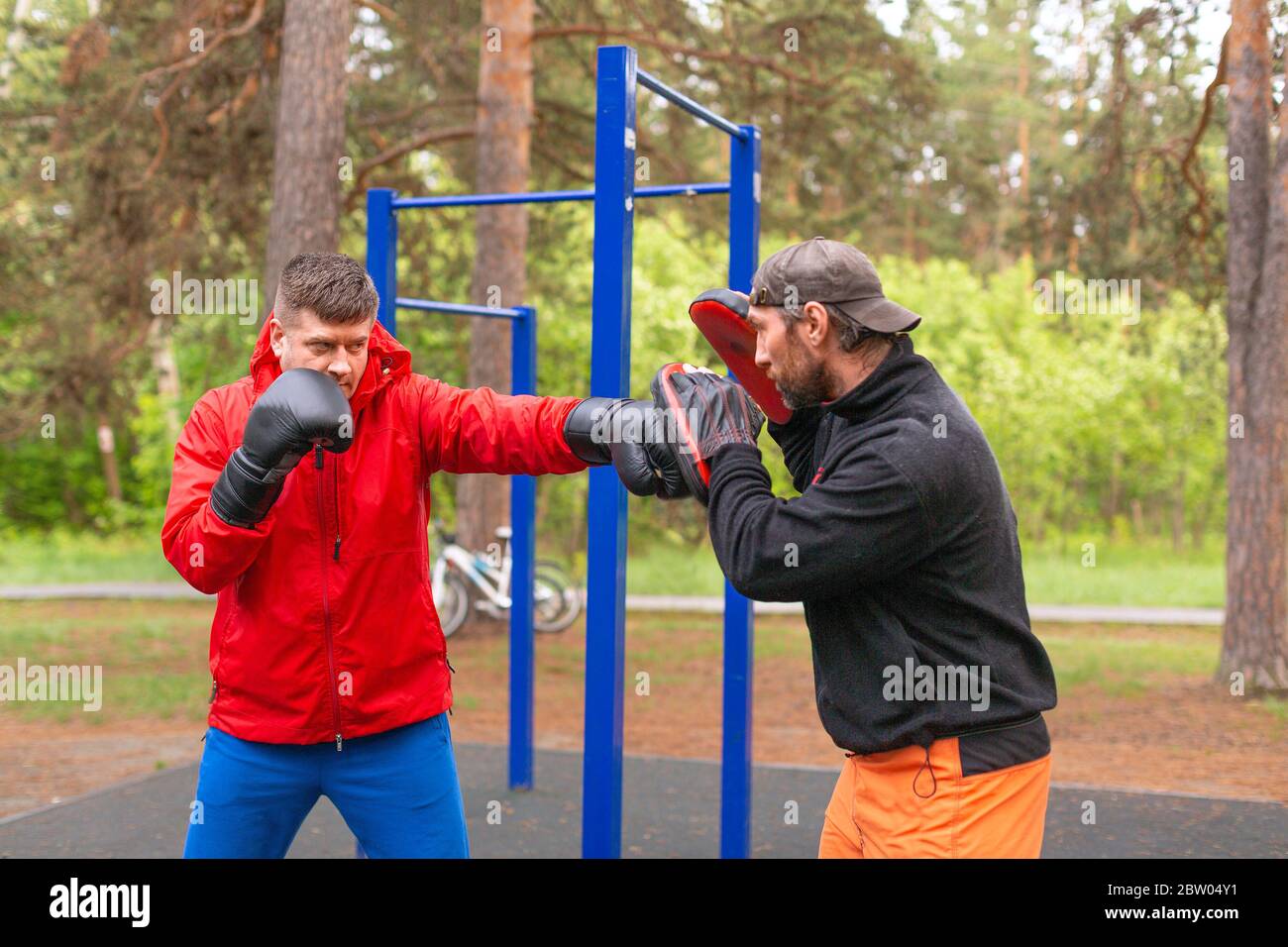 Middleaged boxer training with coach outdoors. Boxing paws work Stock Photo Alamy