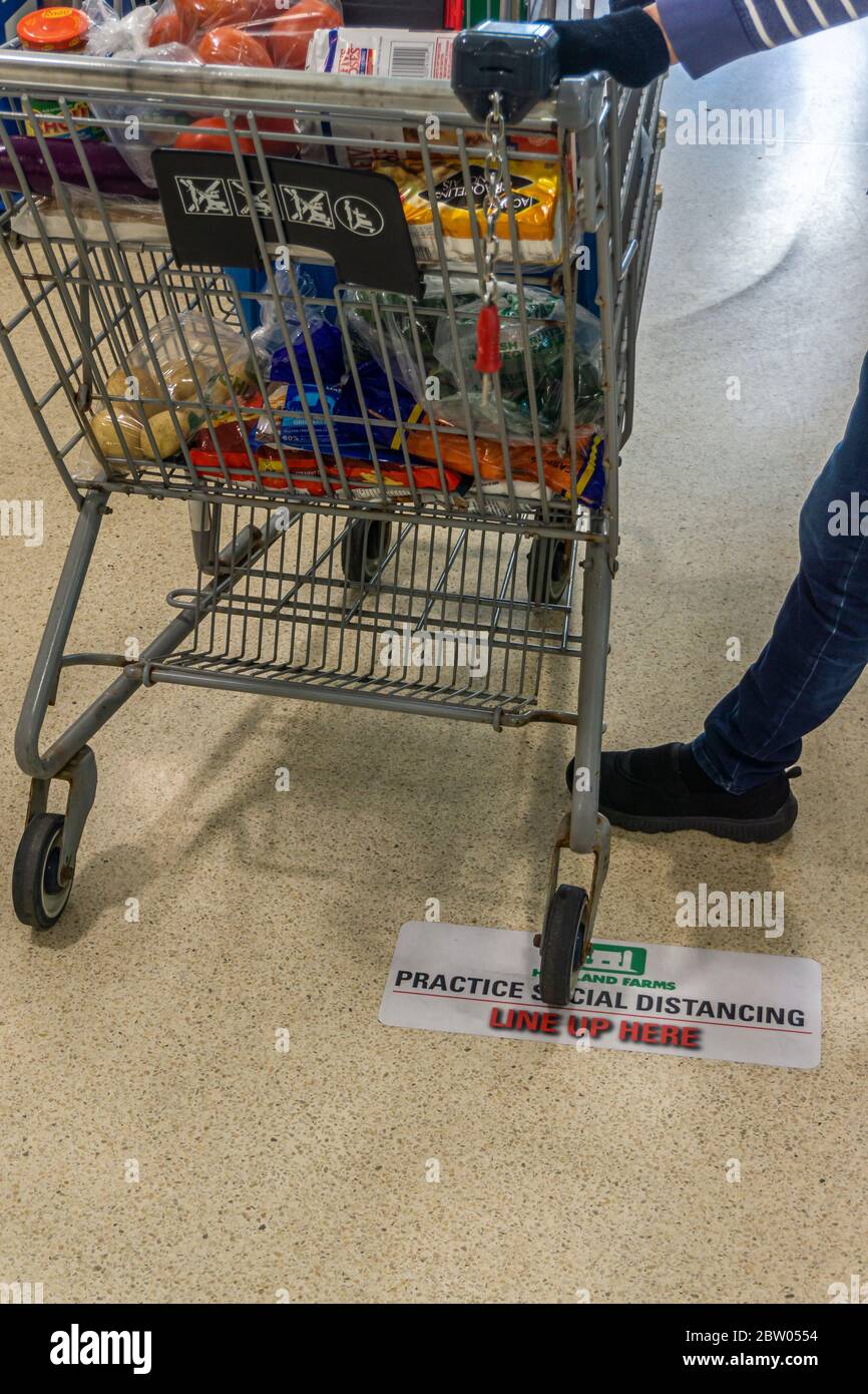 Toronto, Canada, May 2020 - Waiting with grocery cart on social distancing mark on supermarket floor to limit the spread of Coronavirus disease. Stock Photo
