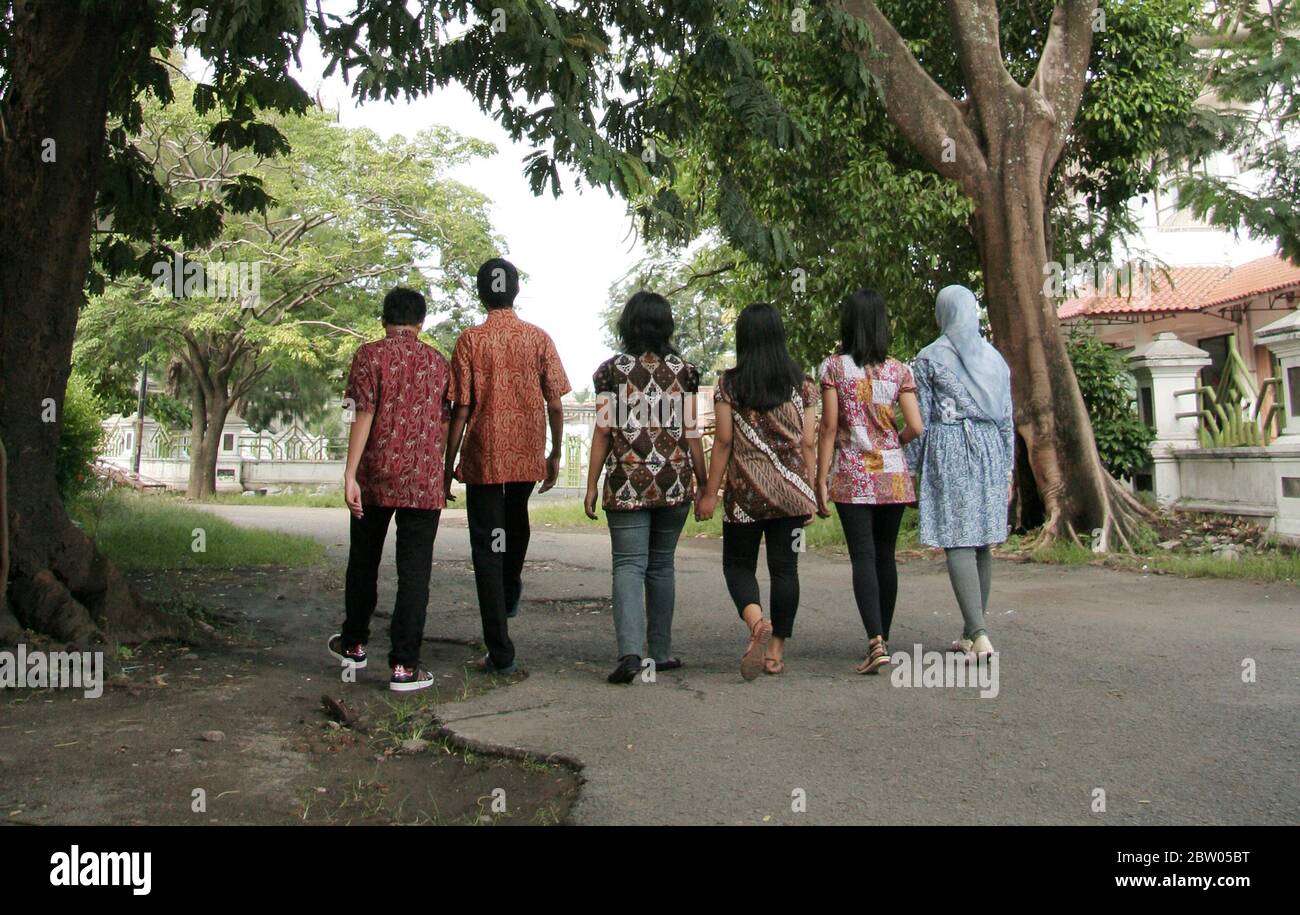 Teenagers wearing batik clothes, they walk together. Viewed from behind at Sriwedari, Surakarta, Indonesia Stock Photo