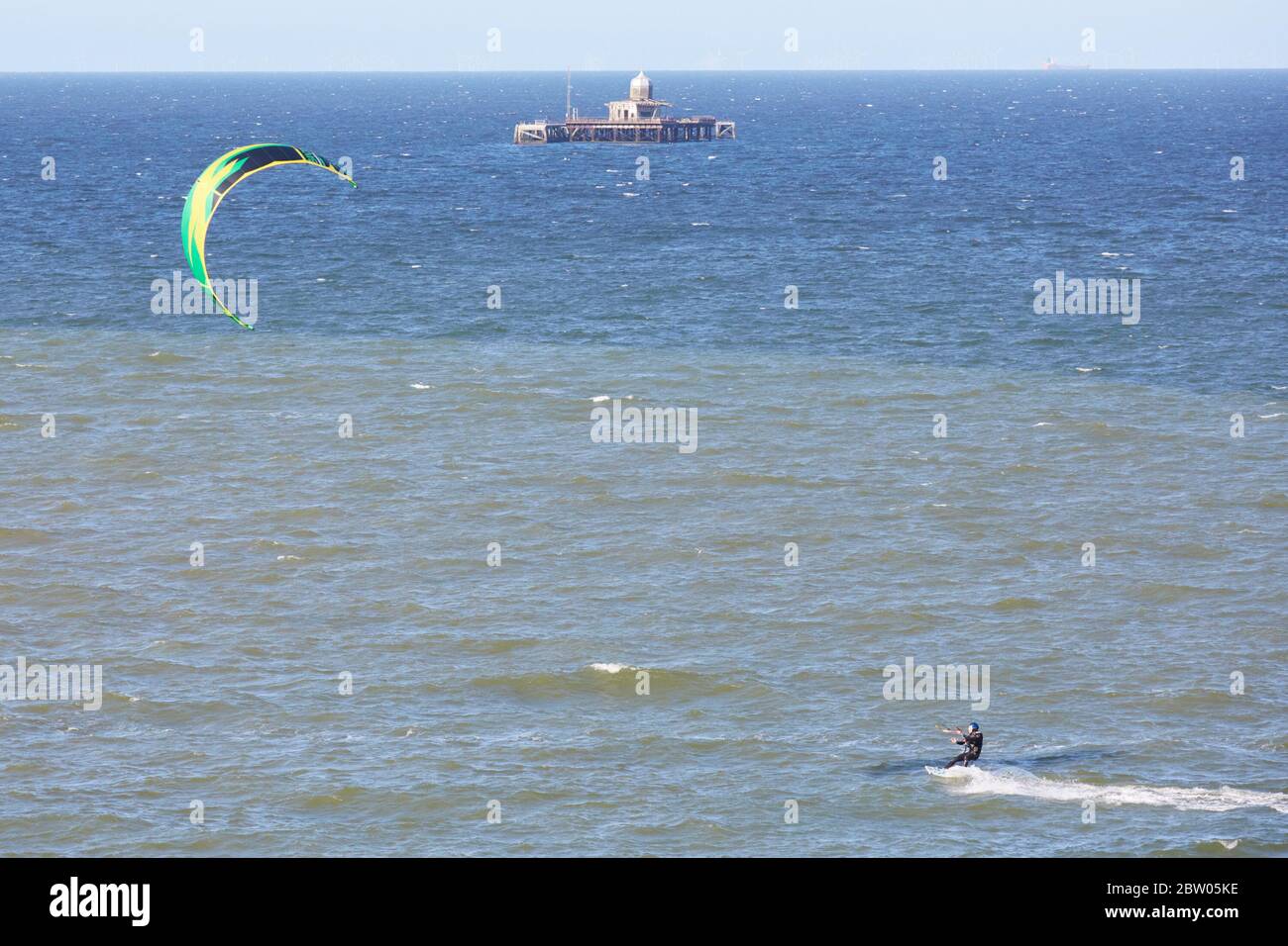 Herne Bay, Kent, UK. 28th May 2020: UK Weather. Kite surfers and windsurfers take advantage of the North East breeze with the abandoned old pier head beyond on a fine sunny day which is cooler than it has been. Credit Alan Payton/Alamy Live News Stock Photo