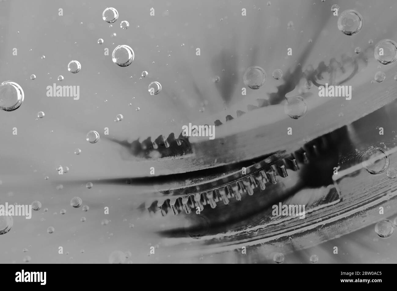 Metal gears in liquid or oil with bubbles. Black-and-white. Oil change in mechanisms, engines, motors Stock Photo