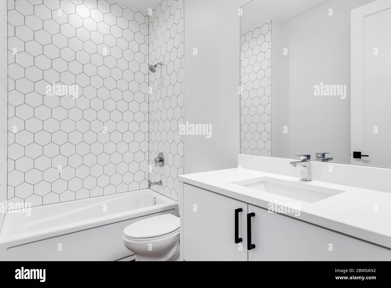 A plain white bathroom with hexagon ceramic tile pieces lining the wall