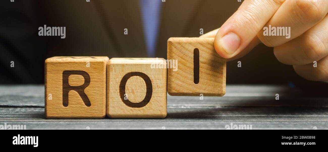 Businessman puts wooden blocks with the word ROI. Return on investment concept. Profitability and loss-making of investments. ROMI ( Return On Marketi Stock Photo