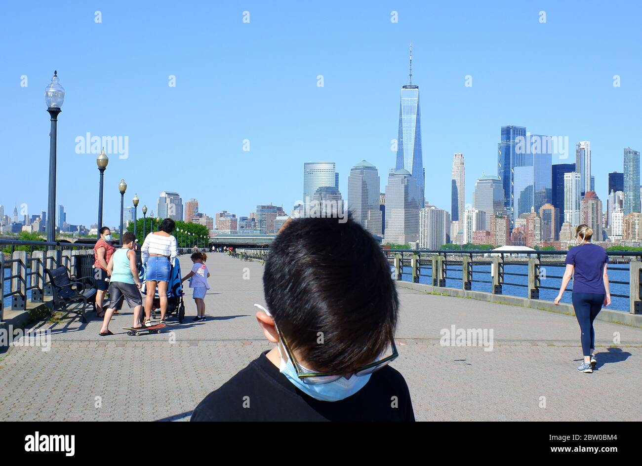 Asian kid wearing mask in Liberty State Park with the skyline of Lower Manhattan, Financial District of New York City in background.Jersey City.New Jersey.USA Stock Photo