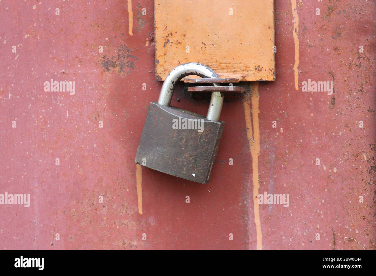 A modern iron padlock hangs on steel the door. Locked door to the premise. Concept of protection, incarceration, protection, prison. Stock Photo