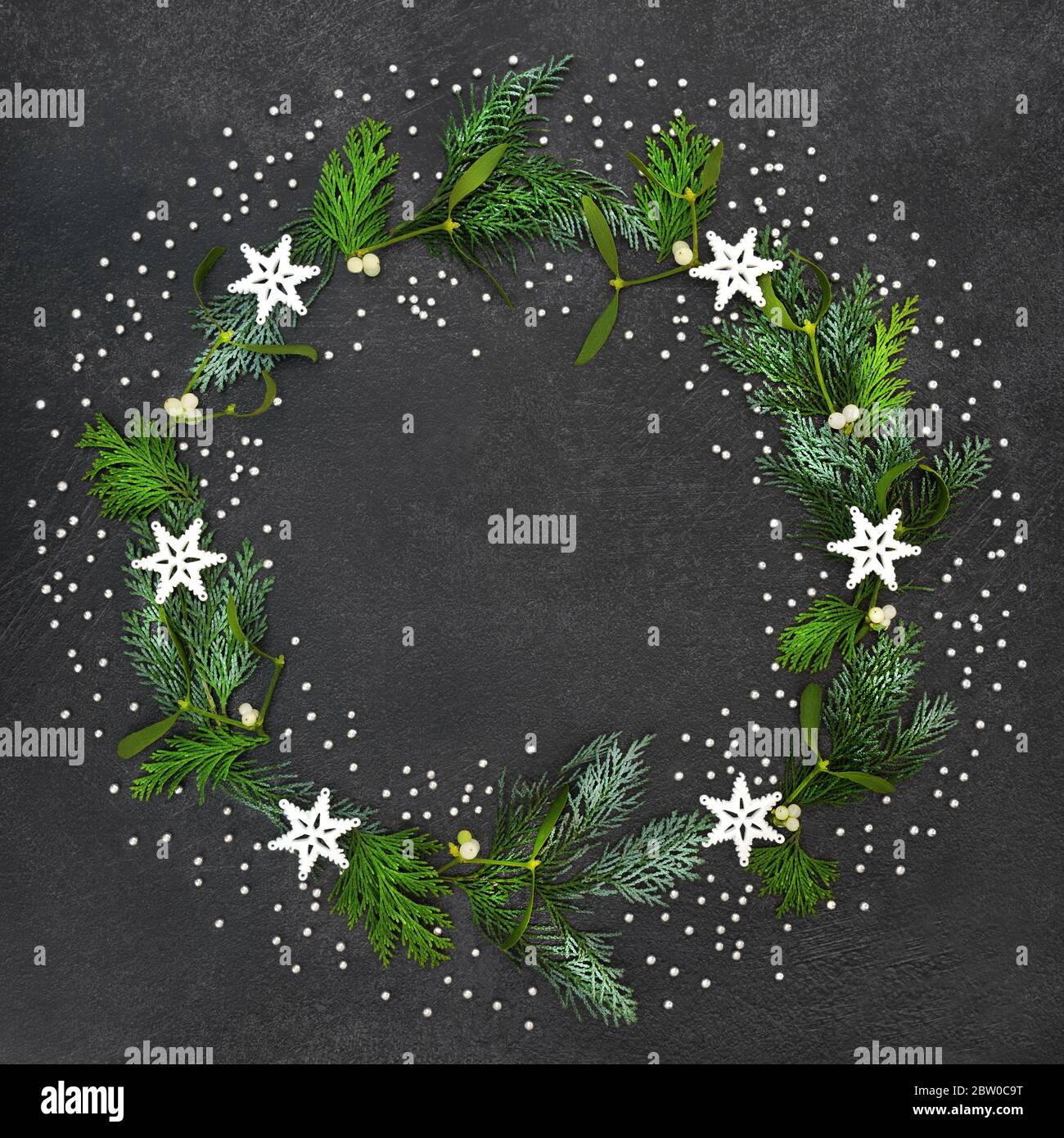 Festive Christmas wreath with stars & decorative silver balls with cedar cypress fir leaves & winter mistletoe on grey grunge background. Xmas & New Y Stock Photo
