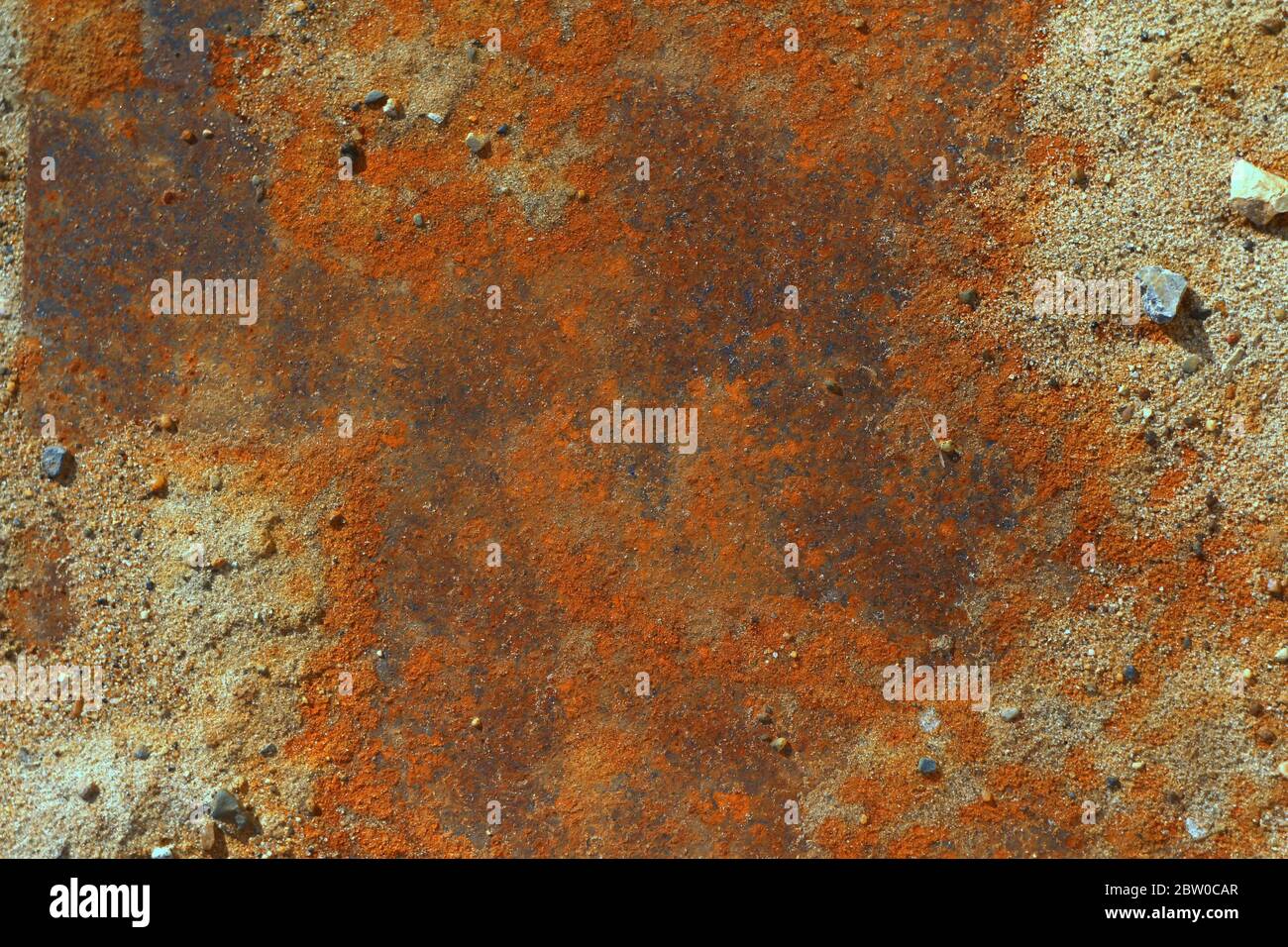 Iron leaf covered with strong deep red and brown rust with sand and stones. The texture of corrosion, wear and destruction. Place for text and background for design. Stock Photo