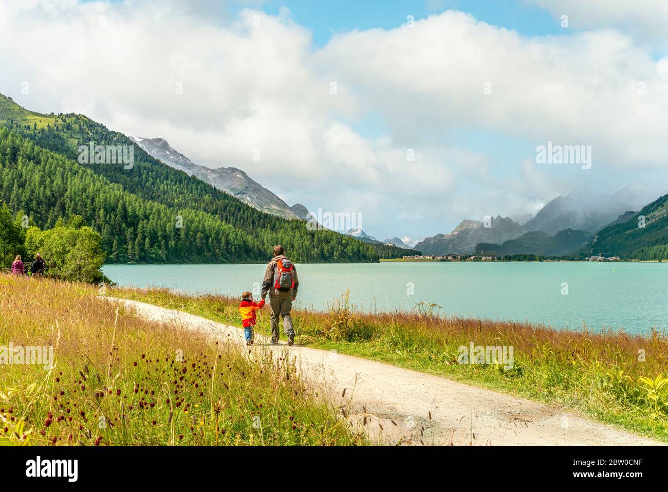 Father and Son hiking lakeside at Lake Silvaplana in a mountain landscape Stock Photo