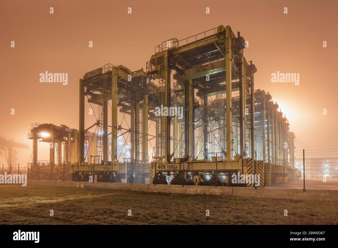 Foggy night scene with heavy equipment at container terminal, Port of Antwerp. It has a modern infrastructure, facilities and equipment. Stock Photo
