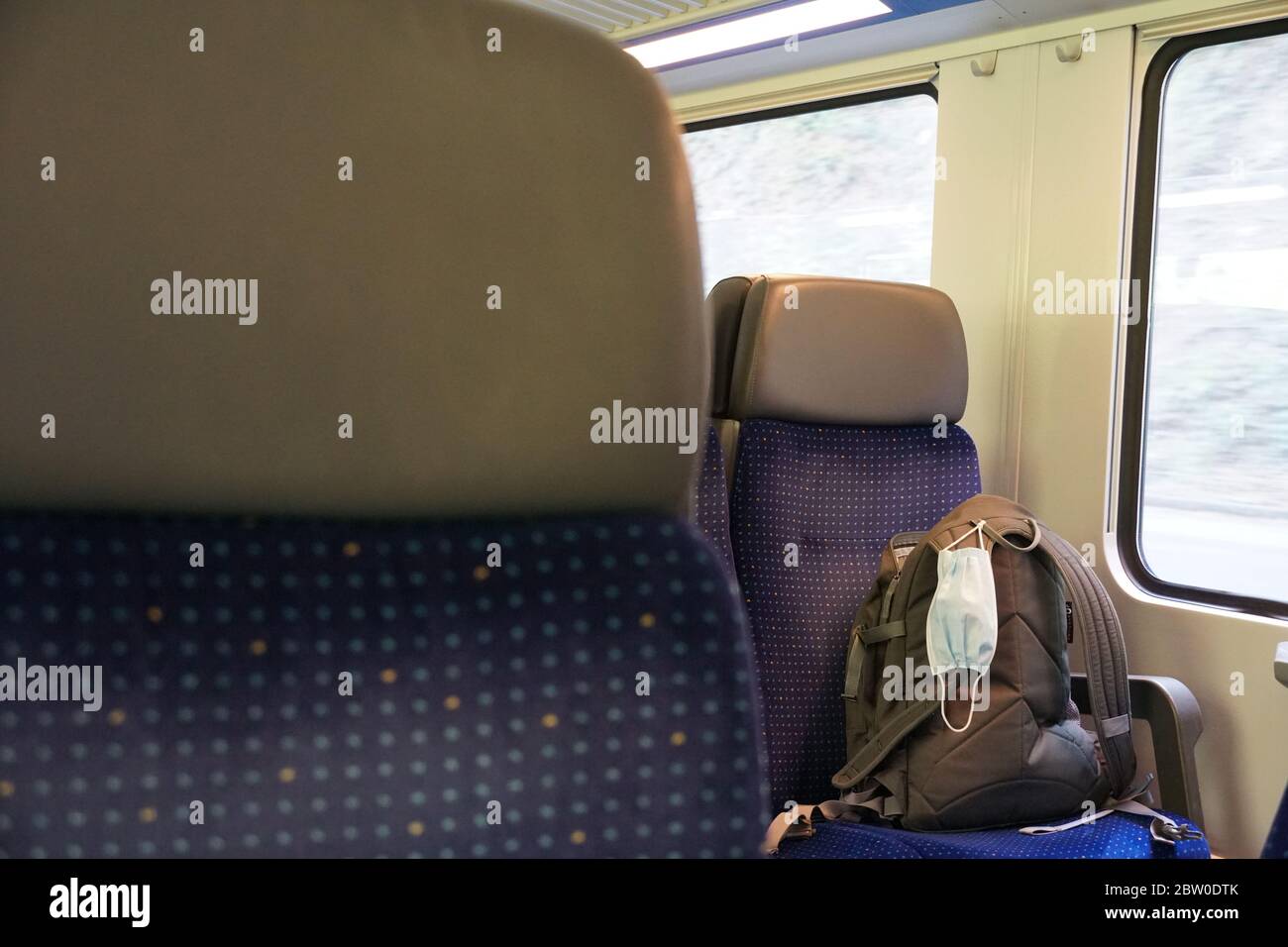 a rucksack on a seat in a train compartment with a N95 facial mask, nose and mouth protection mask, a measure in coronavirus, COVID-19 time, Stock Photo