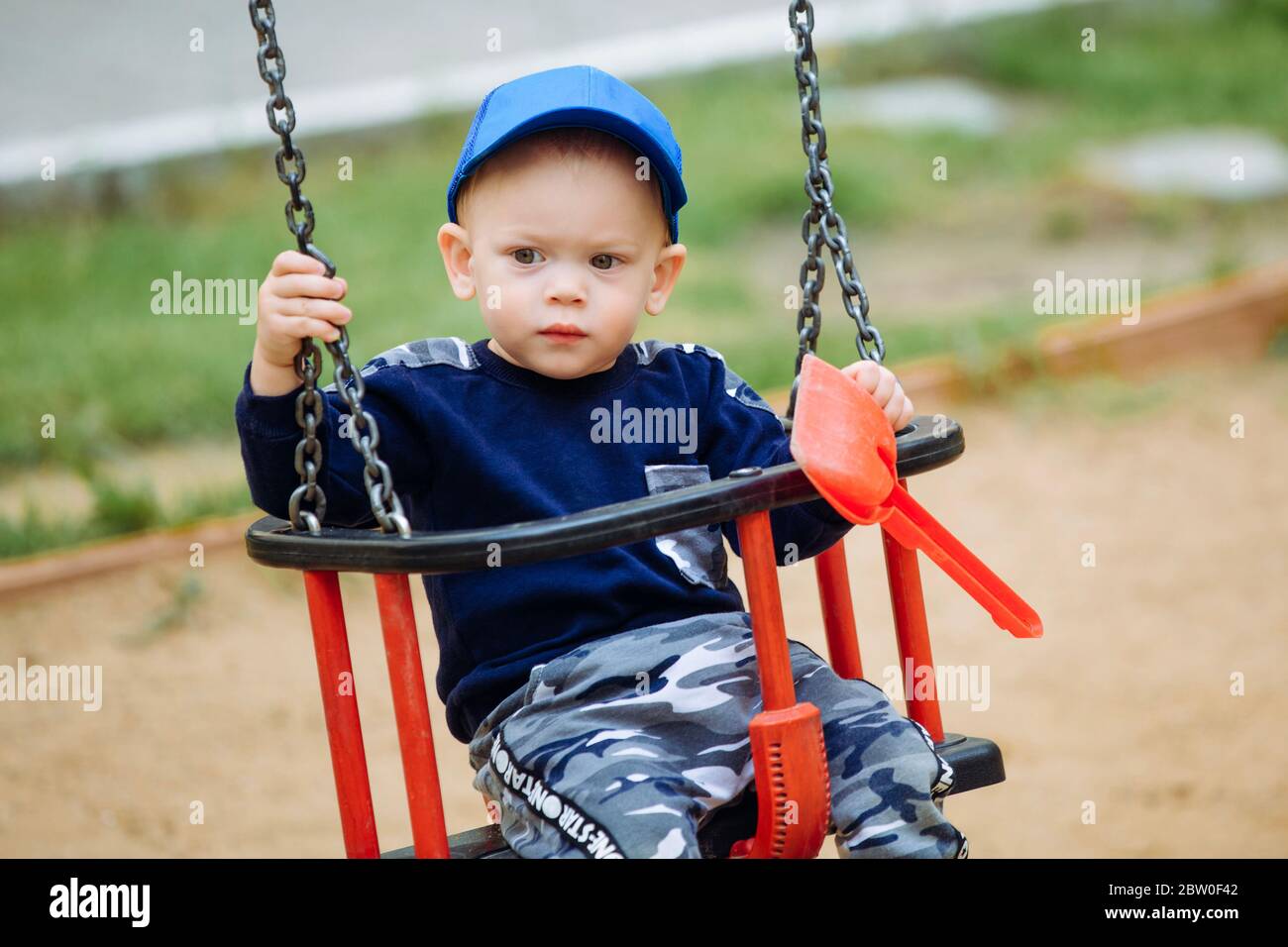 Beautiful child 1-2 years old riding a swing and holding toys in his hands Stock Photo