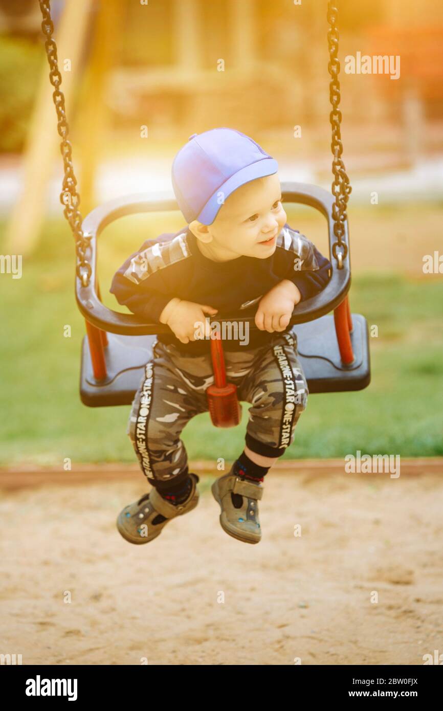 Handsome boy 1-2 years old, sitting on a swing Stock Photo