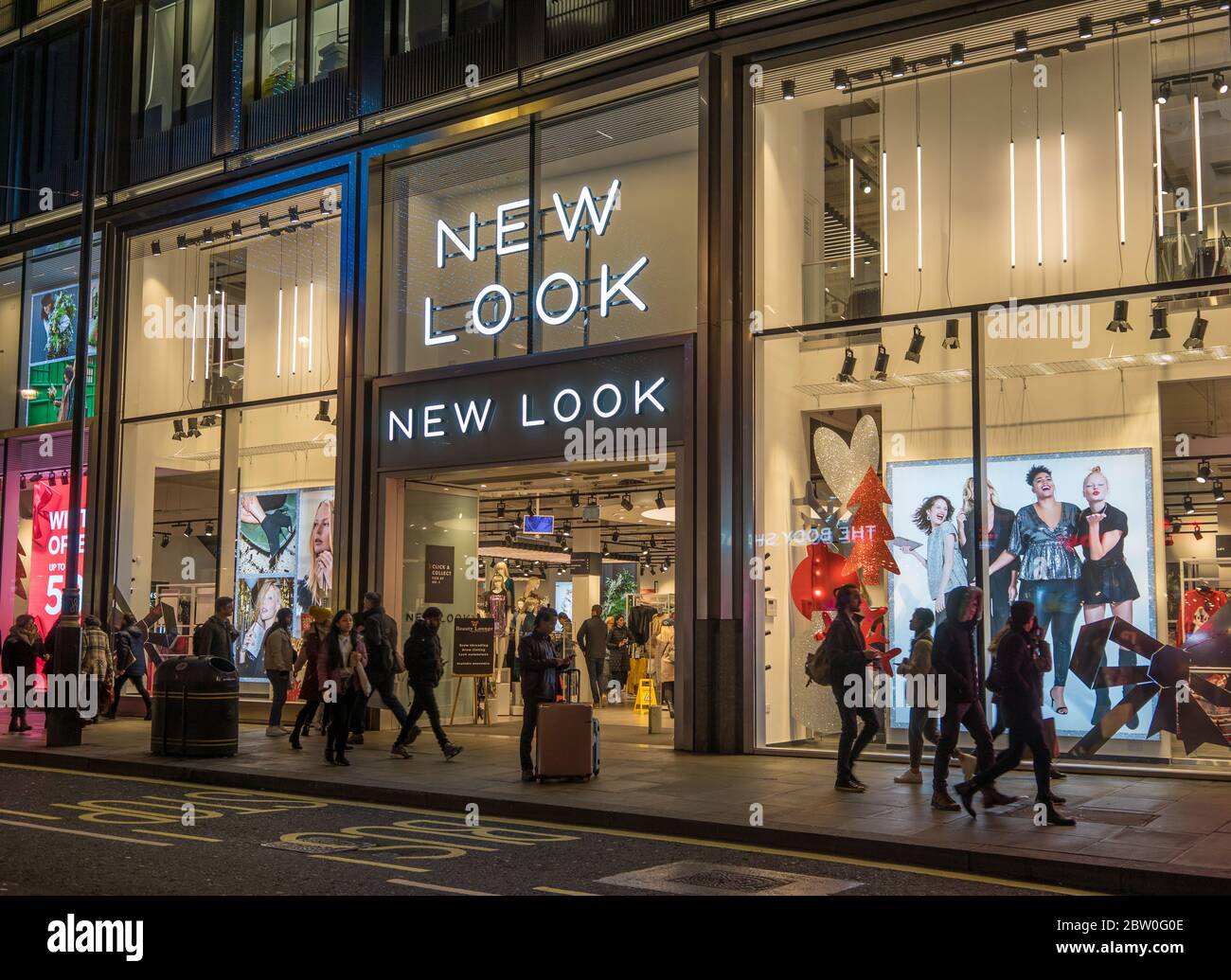New Look store on Oxford Street at night with shoppers walking by. London Stock Photo