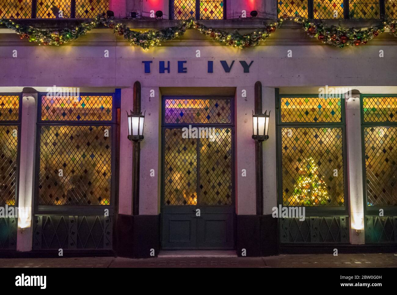 The Ivy Restaurant at night with stained glass windows and Christmas Lights above the sign. London Stock Photo