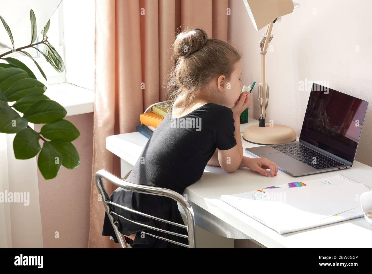 Curious little girl using laptop at desk Stock Photo - Alamy