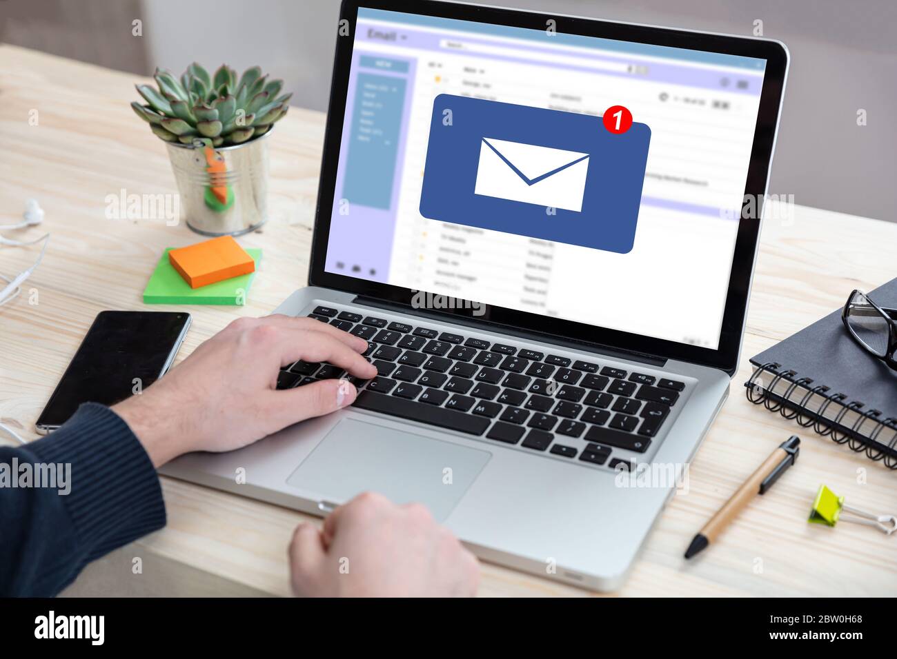 Email notification concept, man working with a computer laptop, one new inbox e mail message on the screen, business office desk background Stock Photo