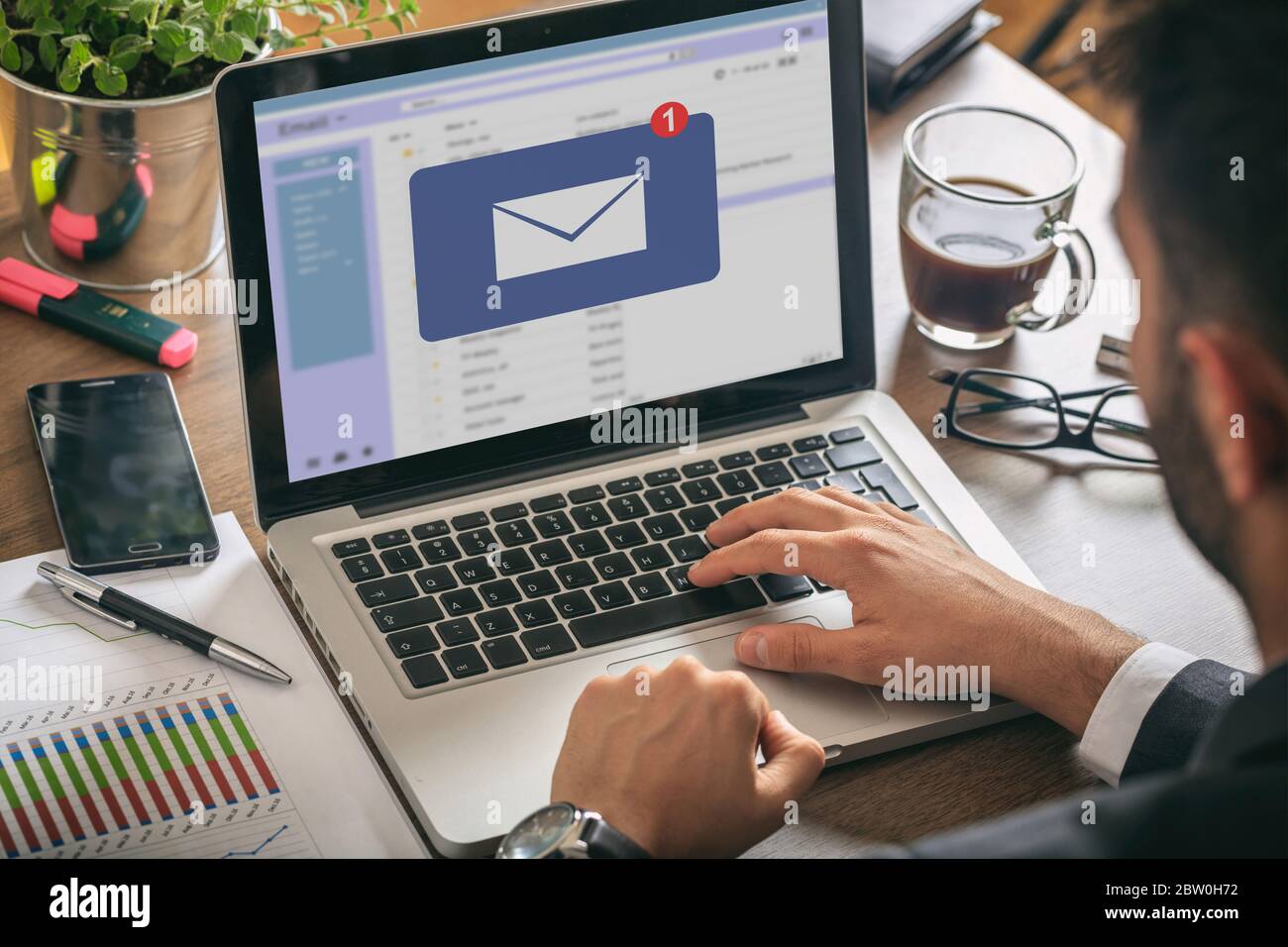 Email notification concept, man working with a computer laptop, one new inbox e mail message on the screen, business office desk background Stock Photo