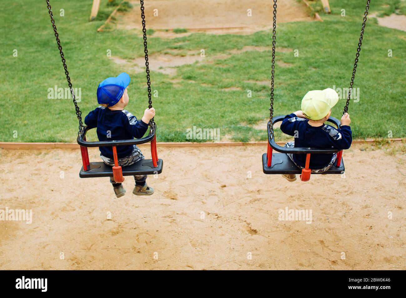 2 twin brothers ride together on a swing, 1-2 years Stock Photo