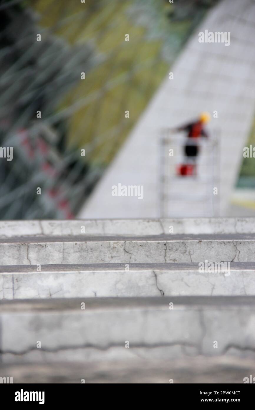 workman cleaning glass windows in blurry background behind grey concrete wall Stock Photo