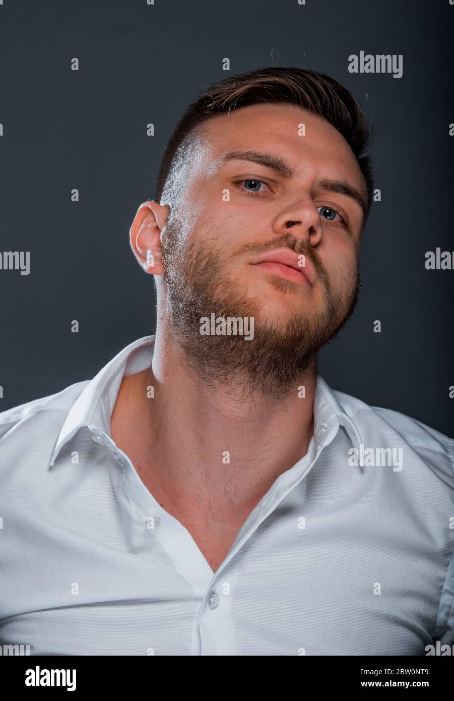 Studio fashion portrait of a young man wearing white shirt while posing ...