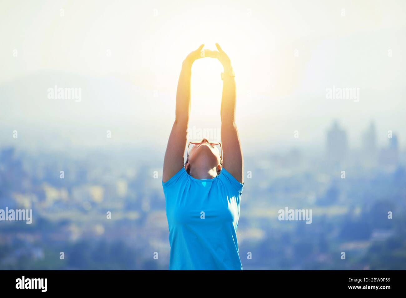 Young fit healthy sportswoman at the mountain or hill top in Murcia, Spain. Beneficial habits and lifestyle. Girl watching sunset over city, open arms Stock Photo