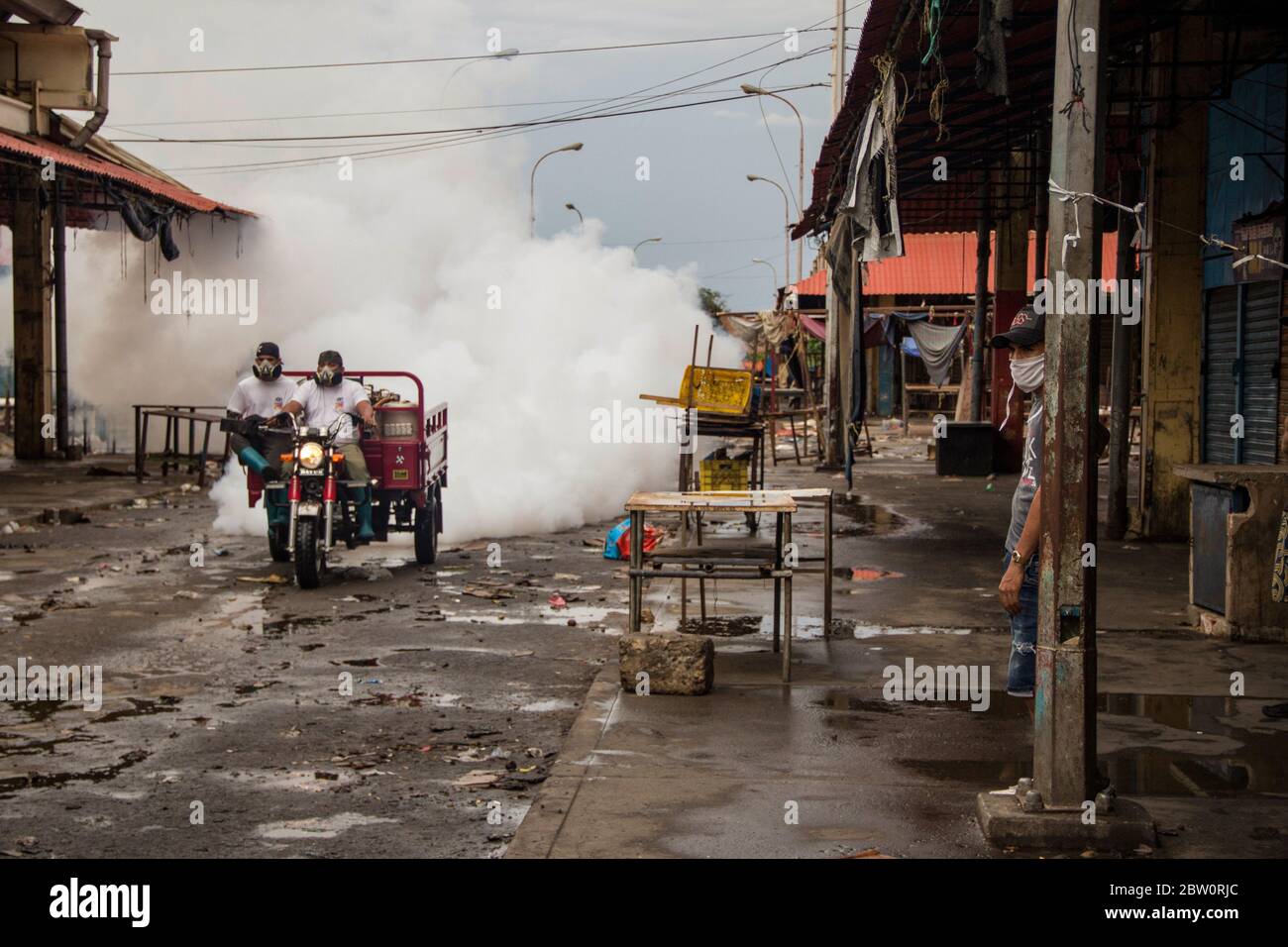 Maracaibo, Venezuela. 28th May, 2020. Two men with face masks drive through the market 'Las Pulgas' and spray disinfectant against the spread of the corona virus. The market, which was considered a critical source of infection, was closed on 24 May. The Venezuelan government has identified 1,245 Covid-19 infected people nationwide. According to official sources, 11 people are believed to have died from Coronavirus. Credit: Maria Fernanda Munoz/dpa/Alamy Live News Stock Photo