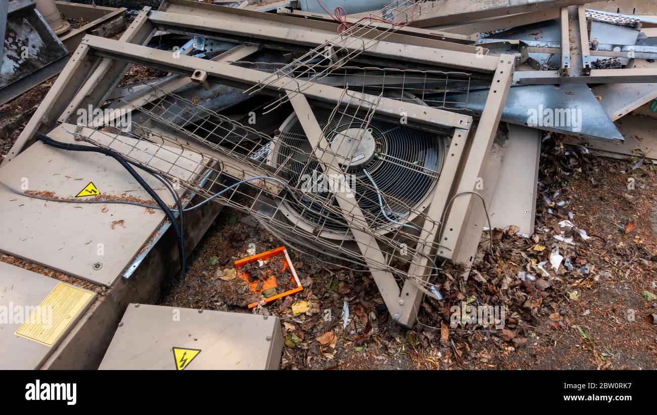 Dismantled industrial water chiller unit laying in a pile of scrap with one of it;s cooling fans and power cabinet Stock Photo