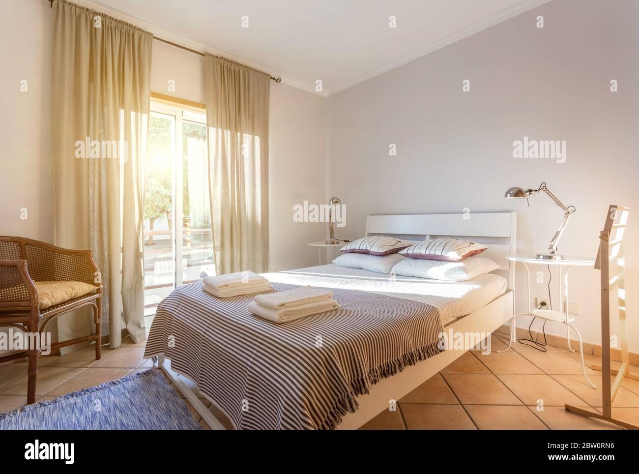 Modern sunny bedroom with a large window. European hotel design. Stock Photo