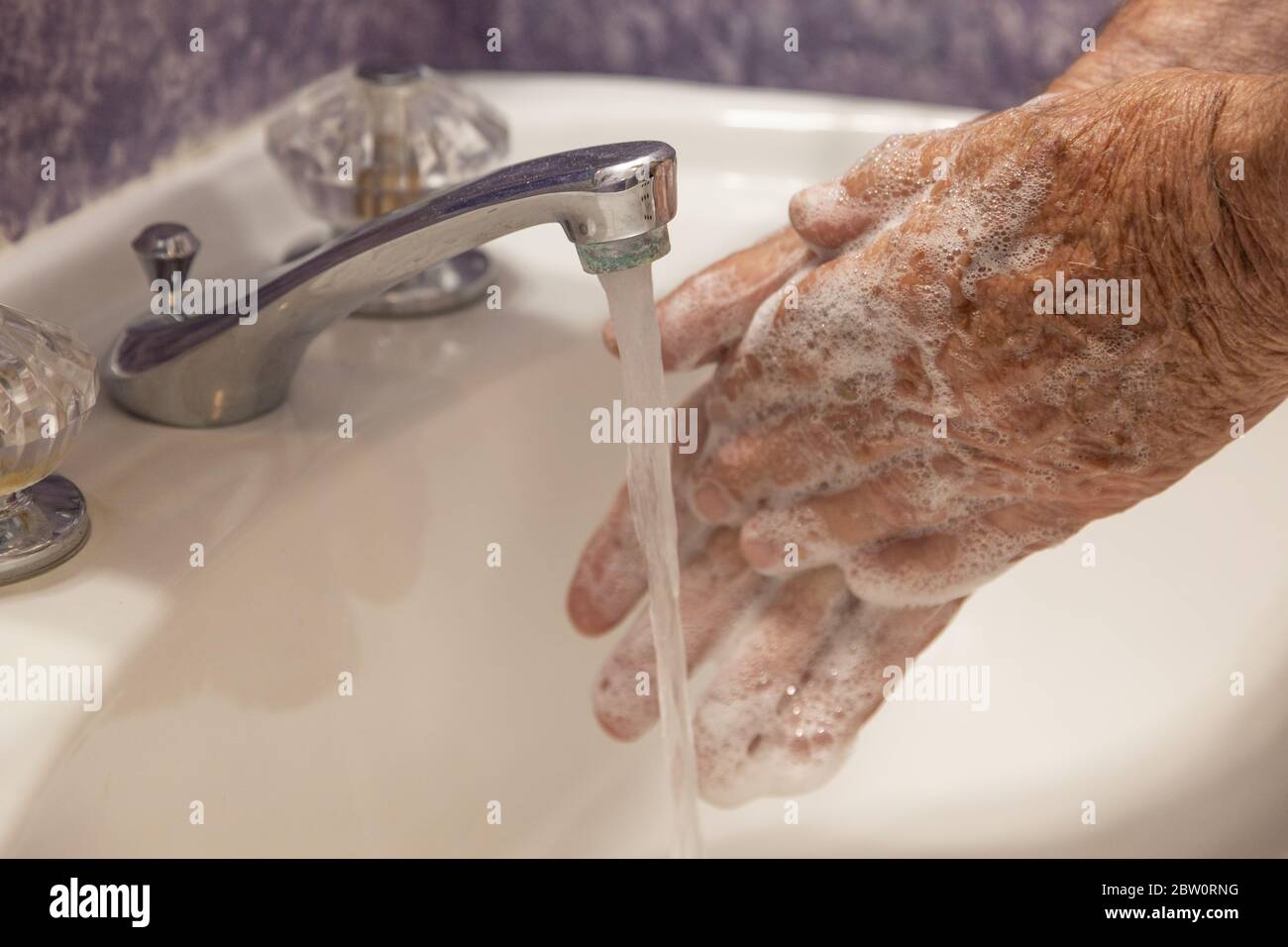 Bathroom sink running water and soapy hands close Stock Photo Alamy