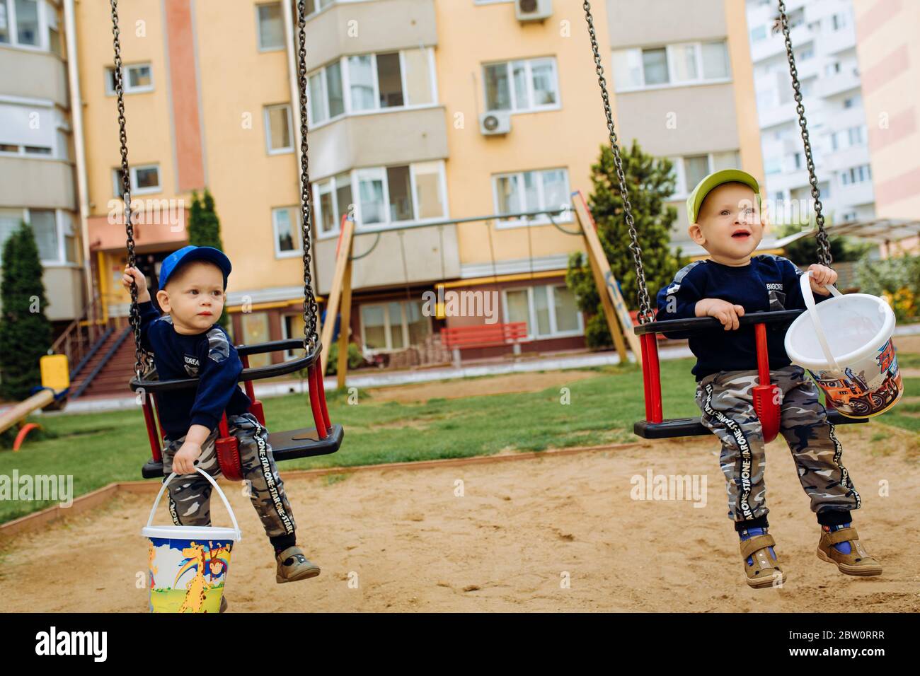2 twin brothers ride together on a swing, 1-2 years Stock Photo