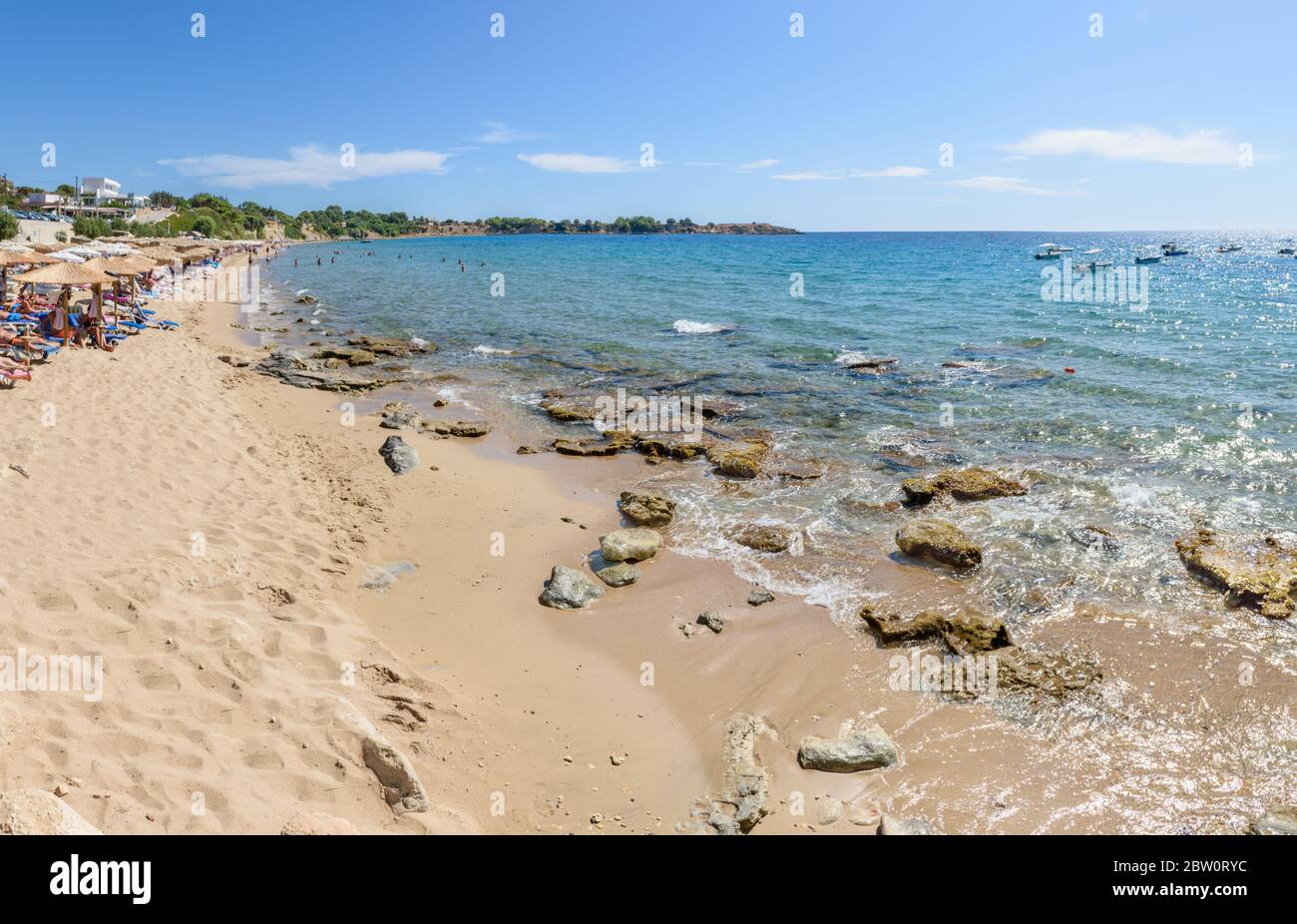 Pefkos beach with holiday-makers, sun beds and umbrellas in village of Pefkos (Rhodes, Greece) Stock Photo