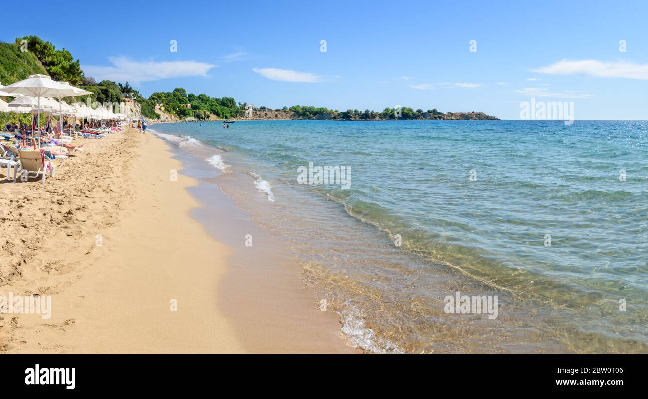 Pefkos beach with holiday-makers, sun beds and umbrellas in village of Pefkos - PANORAMA (Rhodes, Greece) Stock Photo