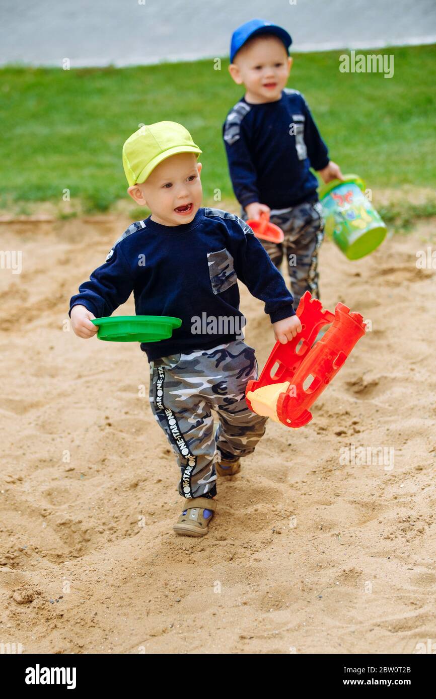 2 twin brothers 1-2 years playing with sand on the playground Stock Photo