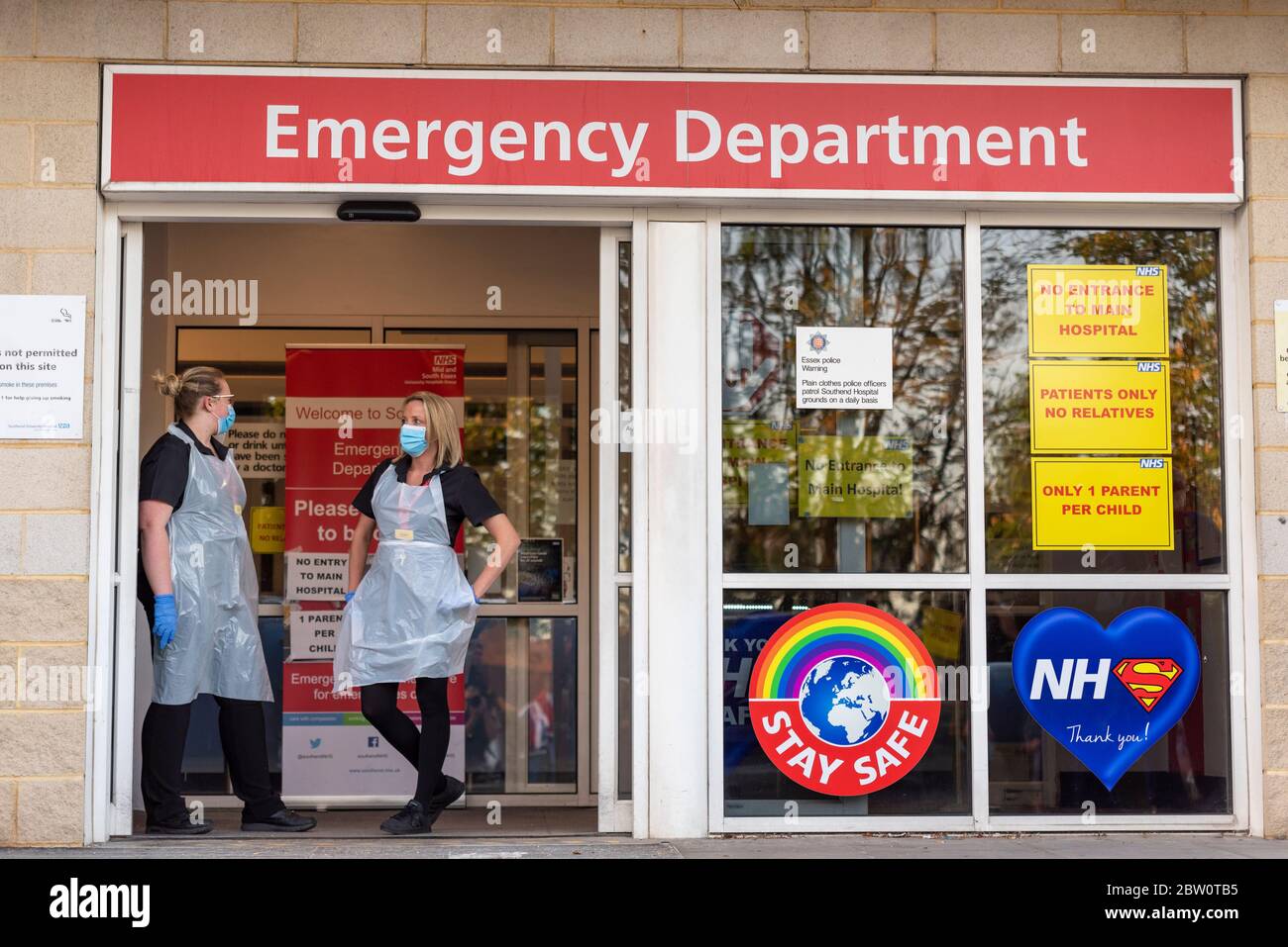 Health staff at Emergency Department entrance at Southend University Hospital, Essex, UK. Two nurses in basic PPE with surgical face masks. COVID-19 Stock Photo