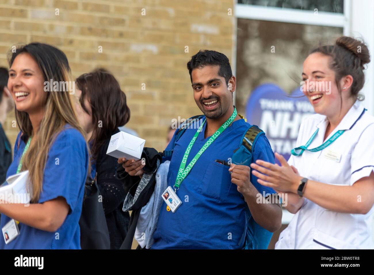 Final clap for carers at Southend University Hospital, Essex, UK at 8pm on Thursday evening. BAME Asian male doctor in scrubs. Health staff Stock Photo