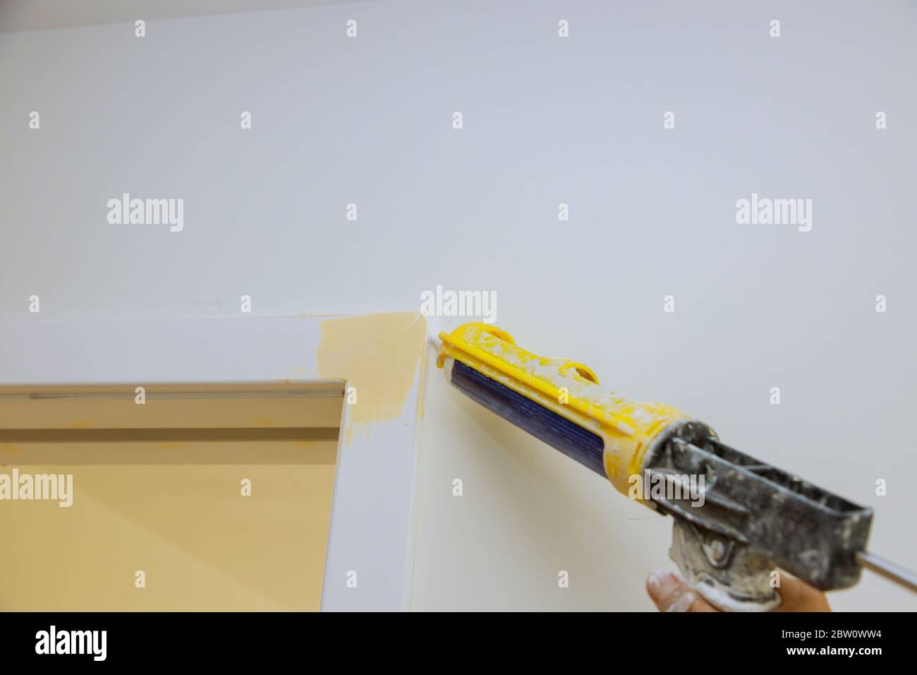 Worker hands applying silicone sealant with caulking gun for repairing