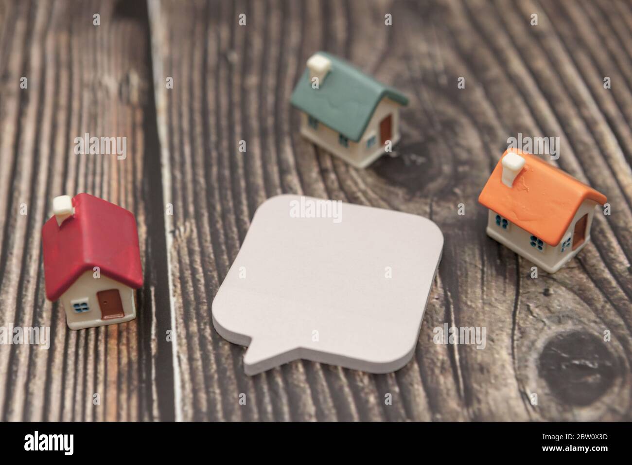 Several colored houses and paper stickers on a wooden background. Stock Photo