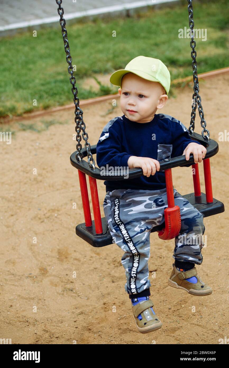 Beautiful boy ride on a children's swing, happy Stock Photo - Alamy