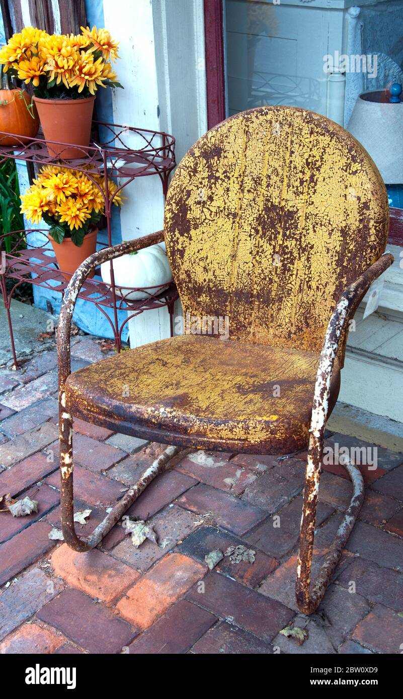 An old rusty metal chair on a brick patio Stock Photo Alamy