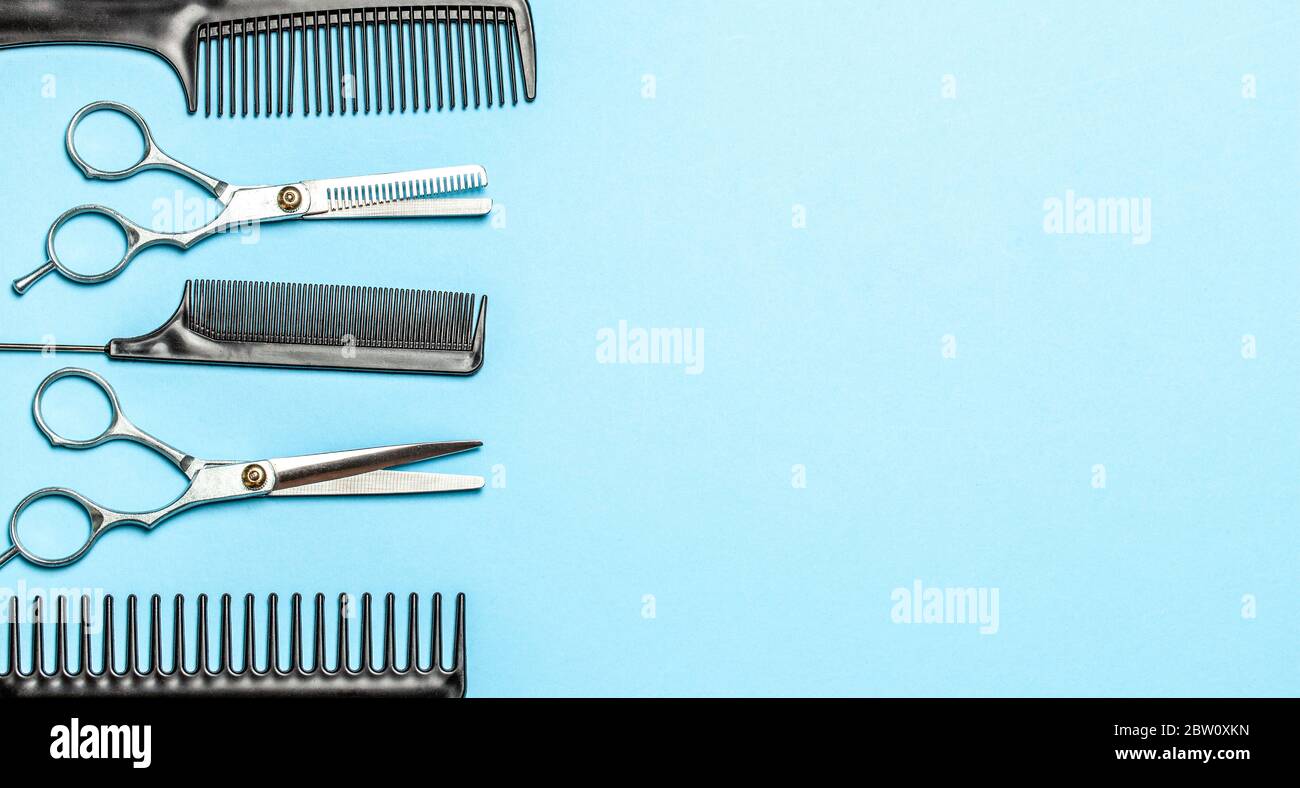Black combs and combs with scissors on blue background. Copy space for text Stock Photo