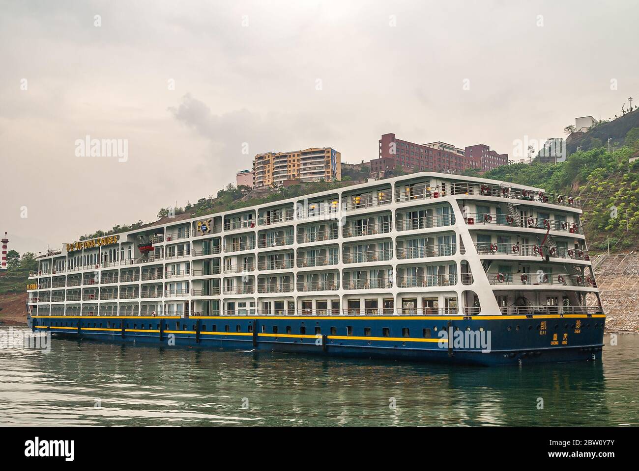 Wushan, Chongqing, China - May 7, 2010: Wu Gorge in Yangtze River. Large hotel river boat of Victoria Cruises moored in green water along shoreline wi Stock Photo