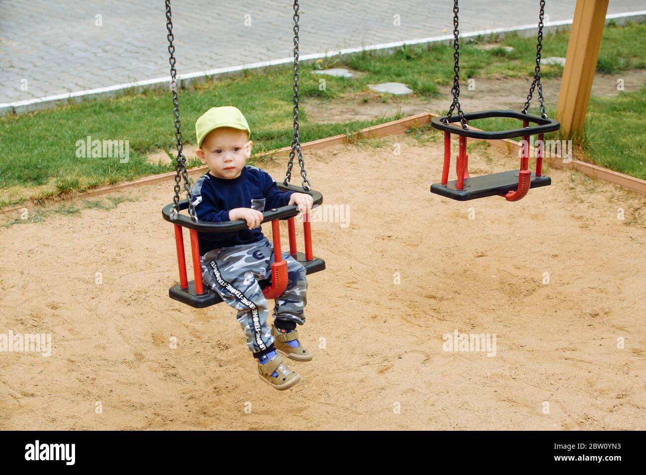 The child is riding on a swing, a playground , 1-2 old year Stock Photo