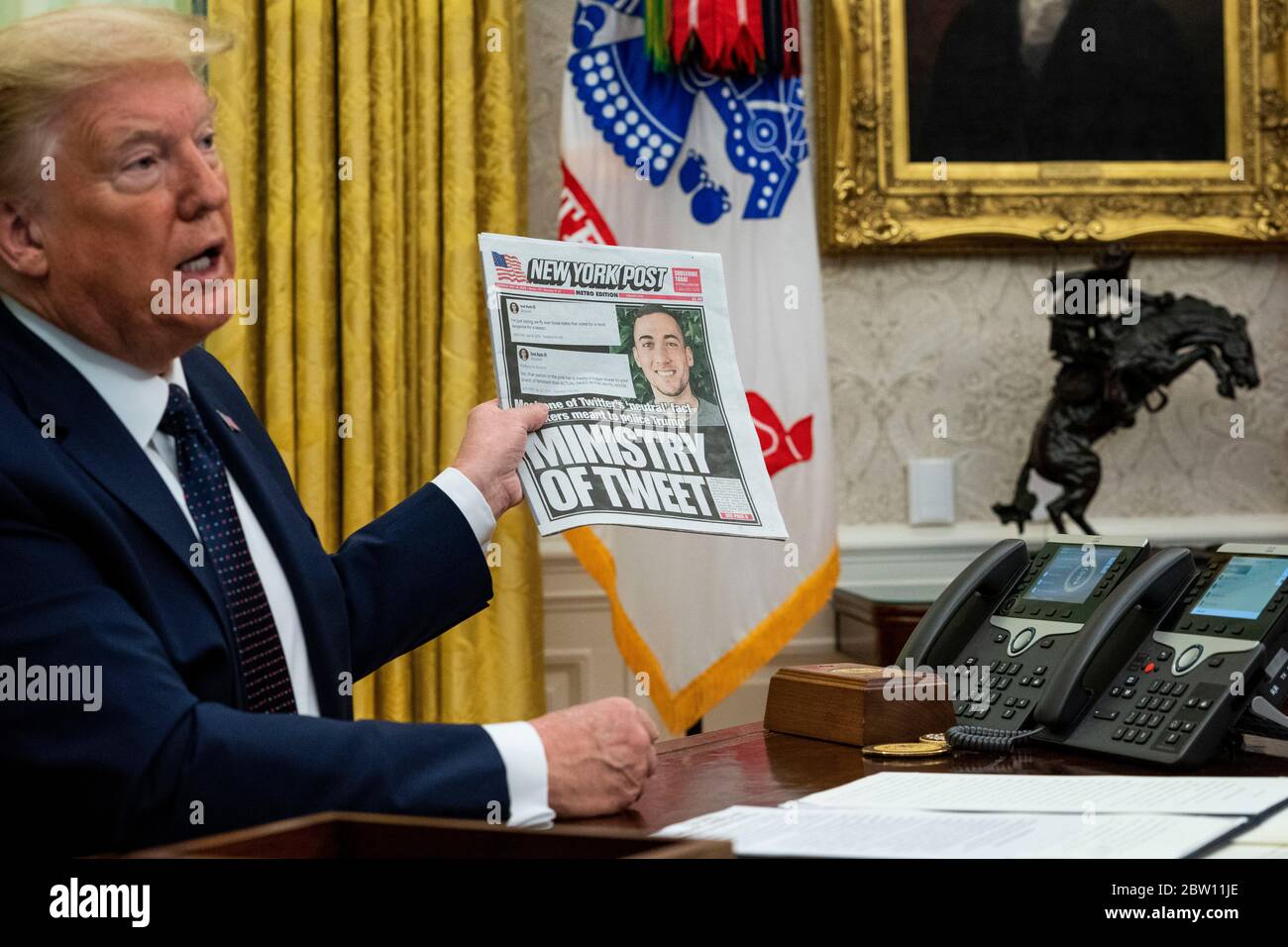 United States President Donald J. Trump, accompanied by US Attorney General William P. Barr, holds a copy of today's New York Post as he makes remarks before signing an executive order in the Oval Office of the White House in Washington, DC that will punish Facebook, Google and Twitter for the way they police content online, Thursday, May 28, 2020. Credit: Doug Mills/Pool via CNP | usage worldwide Stock Photo