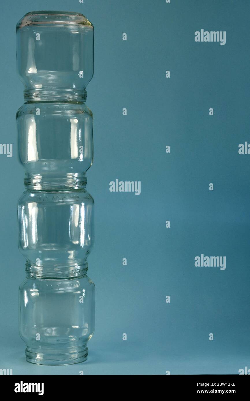 Vertical row of glass four jars on the left on a blue background, vertical frame. Stock Photo