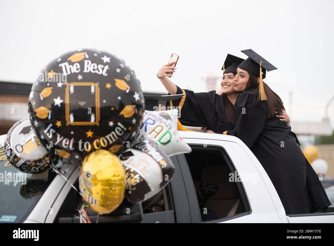 Graduates of Navarro Early College High School, including Esmerelda Alvarez (l) and Alma Pina, parade through their north Austin neighborhood on May 28, 2020 as they celebrate an academic finale shortened by the coronavirus pandemic. About 200 graduates piled into cars, waving at family and friends in the two-mile parade. Credit: Bob Daemmrich/Alamy Live News Stock Photo