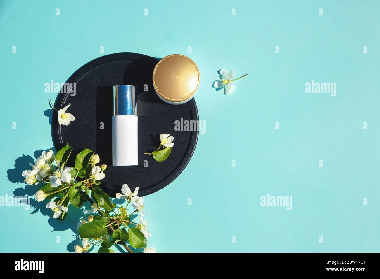 Face cream, elixir for beauty flat lay on a blue background with flowers. Concept of natural
